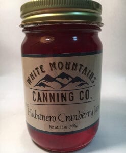 A jar of habanero cranberry jam on top of a table.