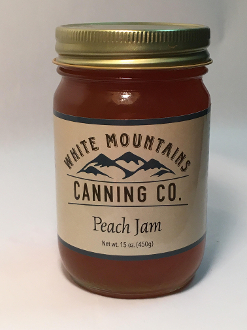 A jar of peach jam on top of a table.