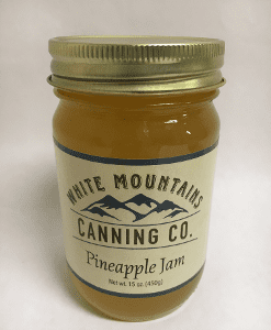 A jar of pineapple jam on top of a table.