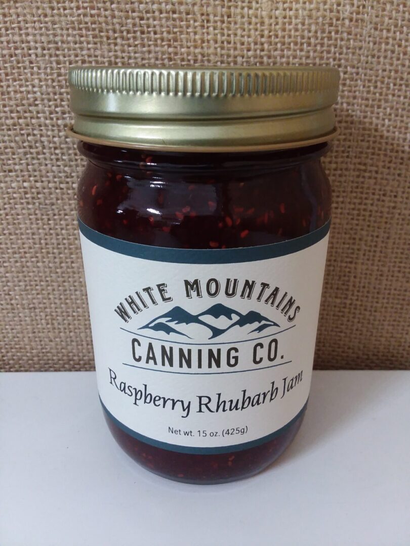 A jar of raspberry rhubarb jam on top of a table.