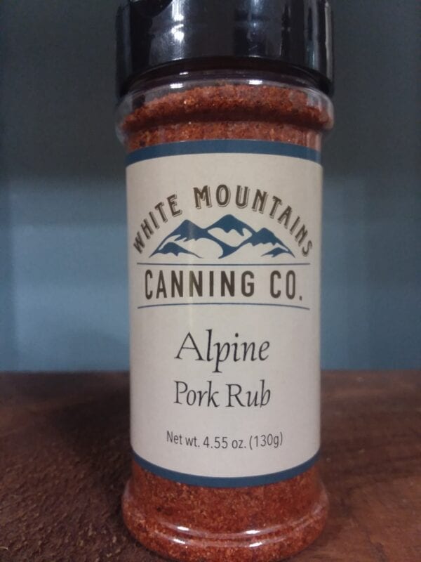 A jar of alpine pork rub on top of a table.