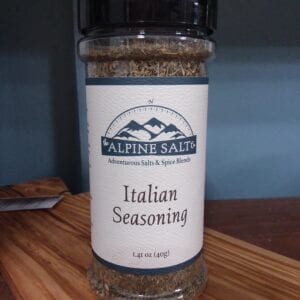 A jar of seasoning sitting on top of a wooden table.
