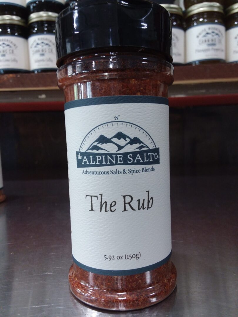 A jar of the rub is sitting on a counter.