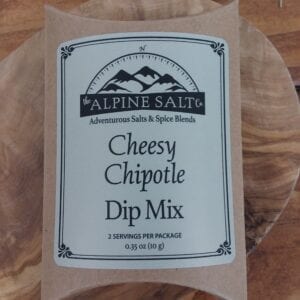 A package of cheesy chipotle dip mix on top of a wooden table.
