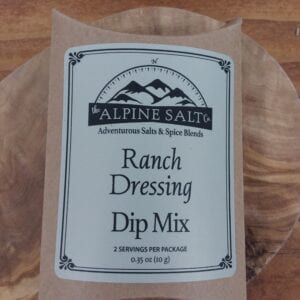 A bag of ranch dressing dip mix sitting on top of a wooden plate.