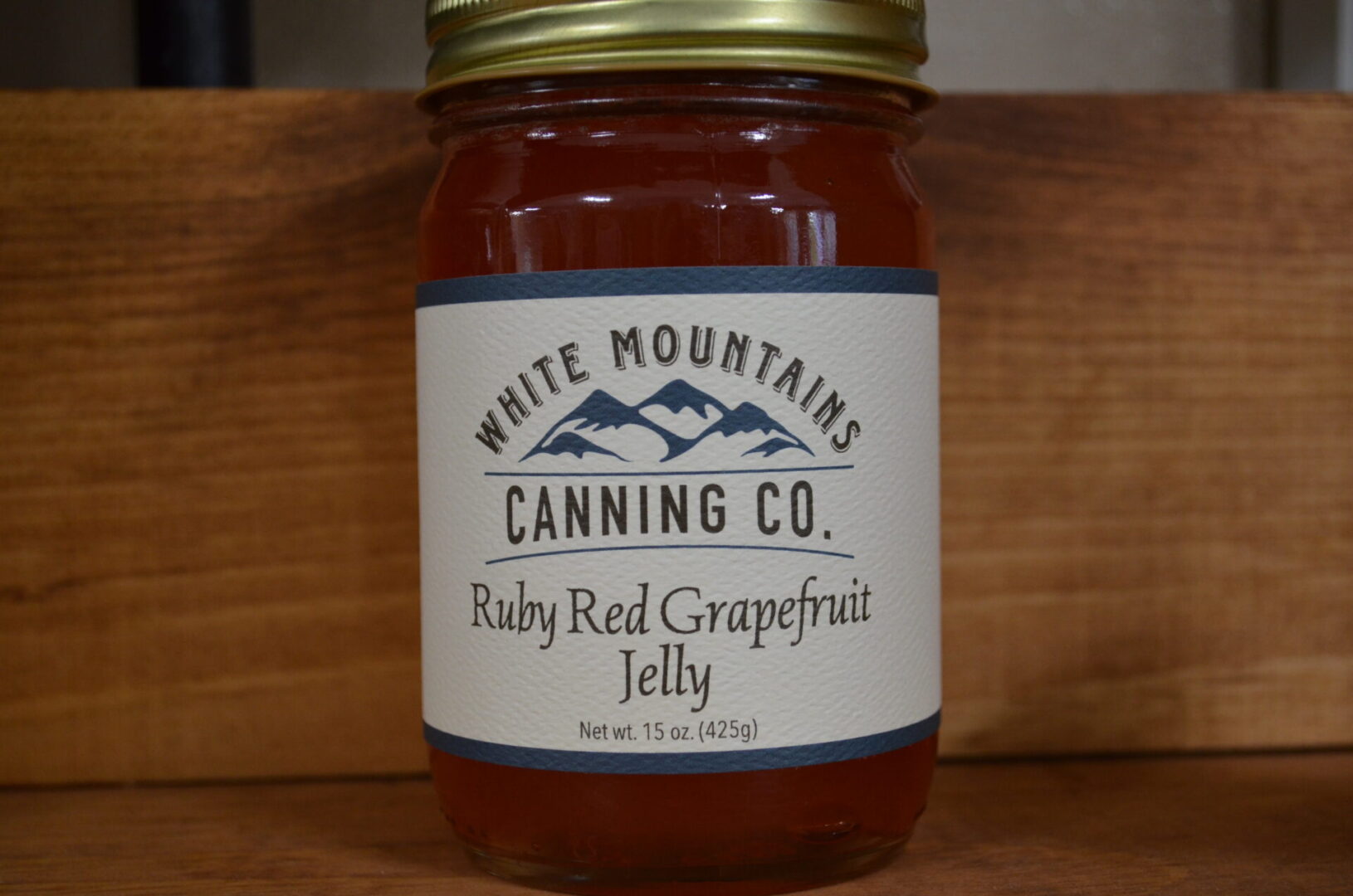 A jar of jelly sitting on top of a wooden table.