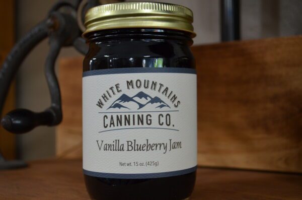 A jar of vanilla blueberry jam on top of a table.
