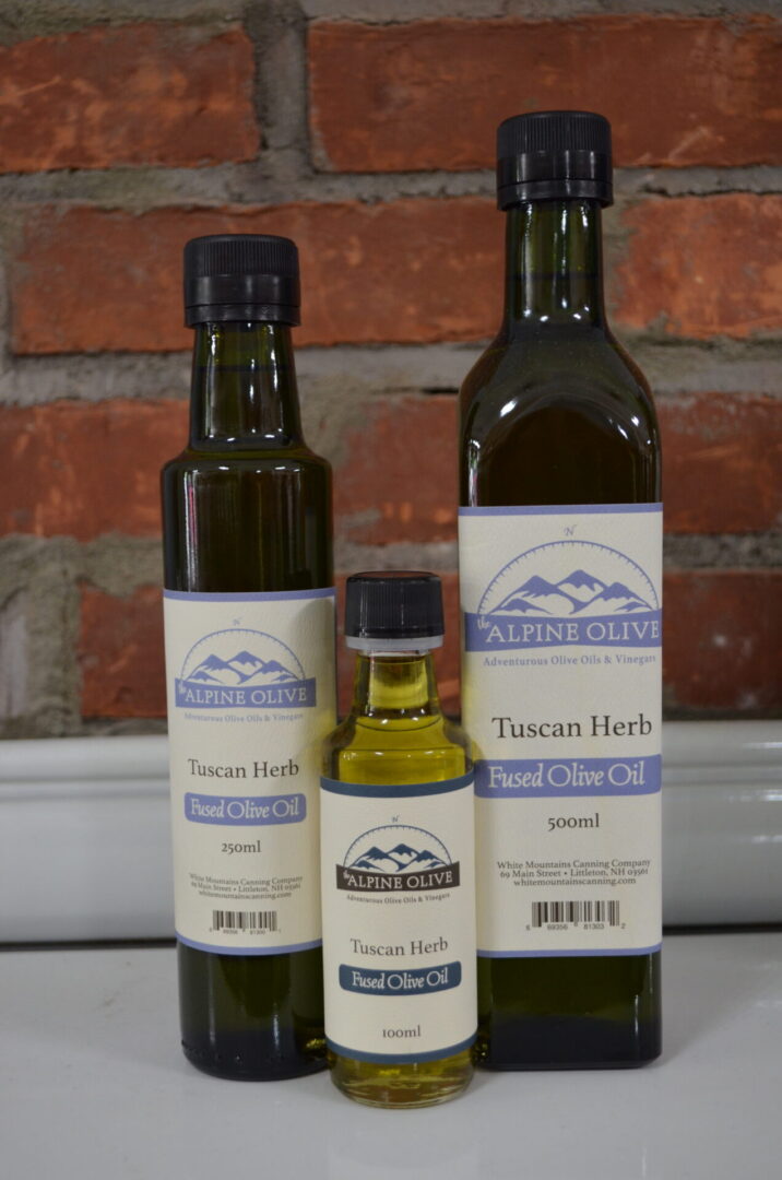 Three bottles of olive oil sitting on a counter.