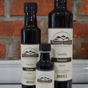 Three bottles of vanilla flavored oil on a counter.