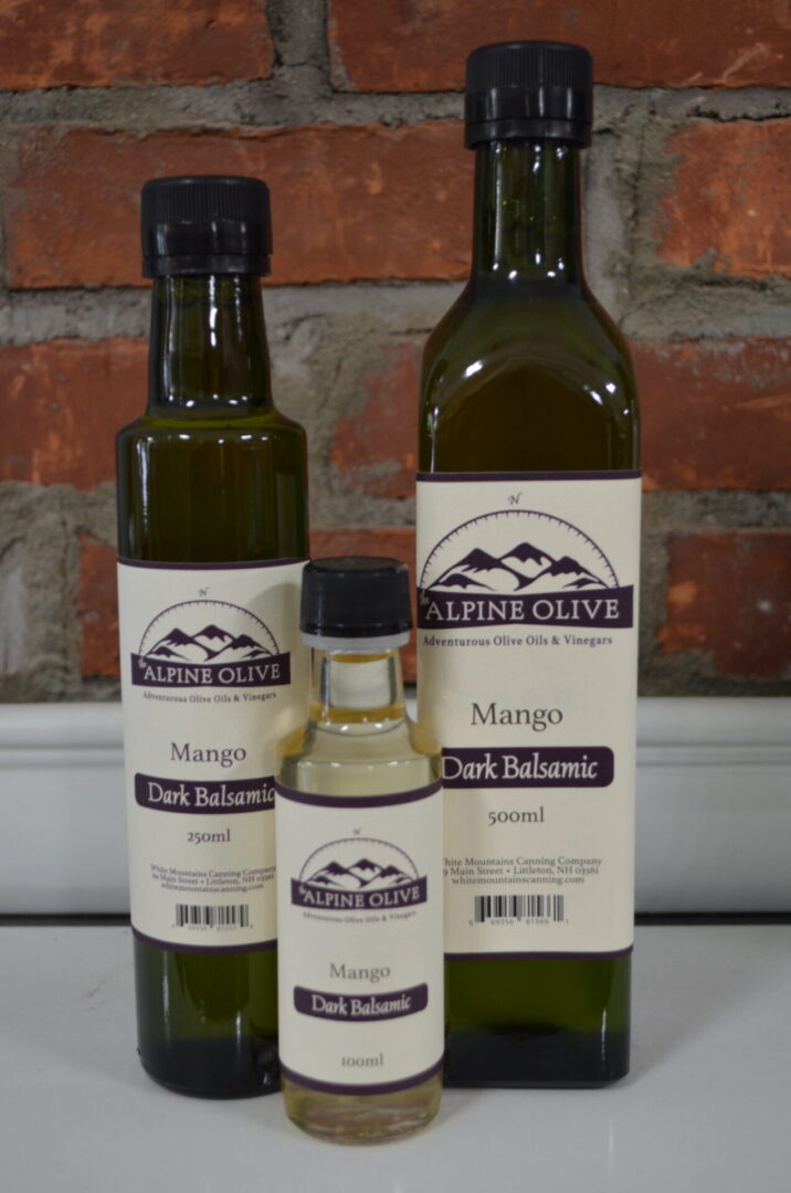 Three bottles of olive oil with a bottle in the background.