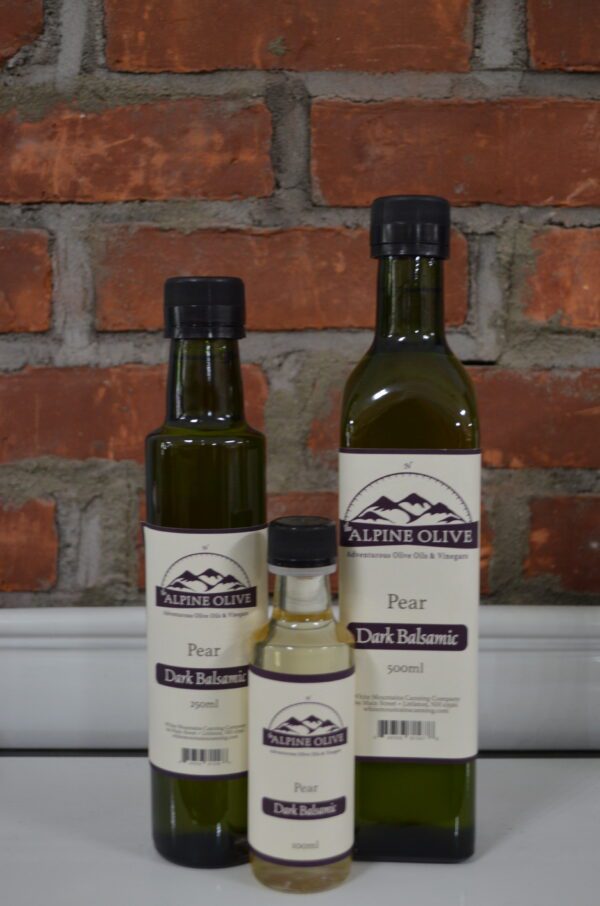 Three bottles of olive oil are sitting on a brick wall.