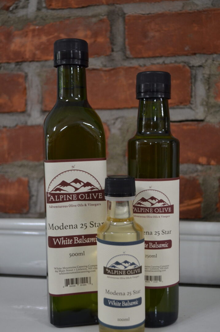 Three bottles of olive oil sitting on a counter.