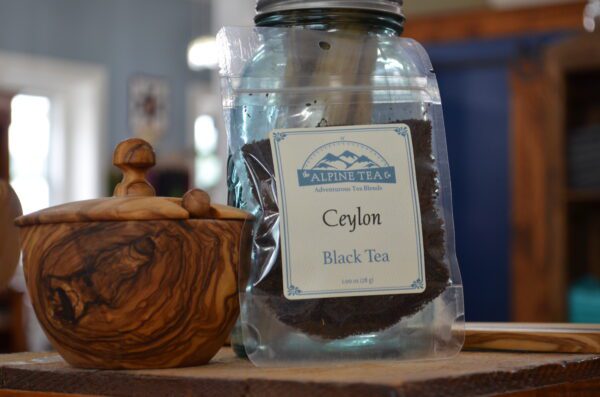 A jar of tea and a wooden bowl on a table.