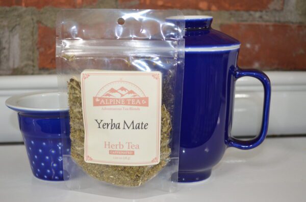 A bag of yerba mate tea sitting next to a blue mug.