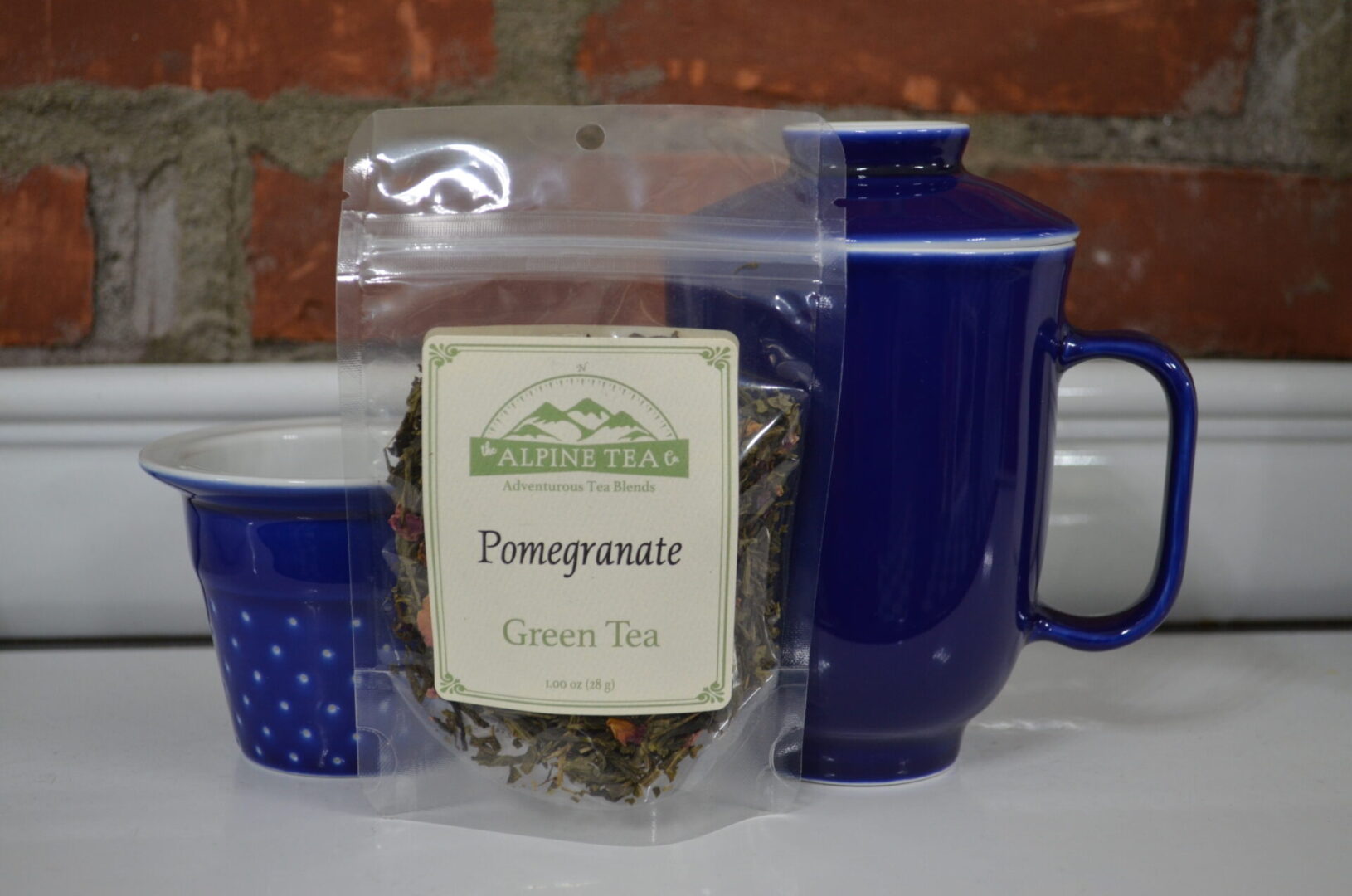 A bag of green tea and two cups on a table.
