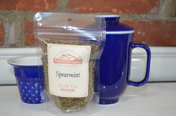 A bag of spearmint tea next to a blue mug.