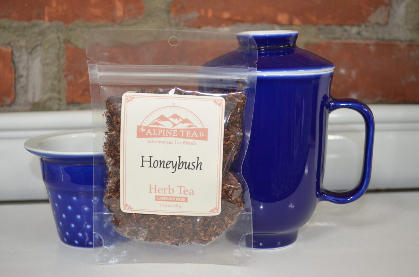 A bag of honey bush tea sitting next to a blue mug.
